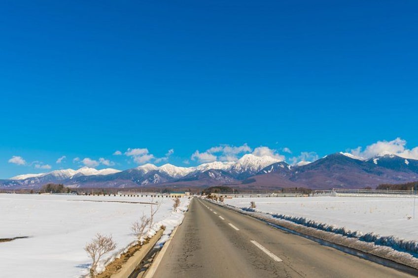 A snow-covered road with mountains in the background. 3