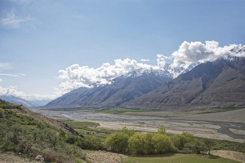A mountainous landscape with a river, green vegetation, and snow-capped peaks. 5