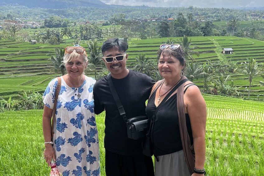 Three people standing in a rice field with terraced hills in the background. 5
