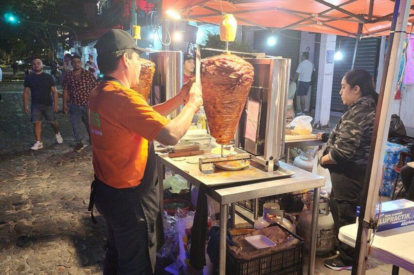 A street food vendor preparing a large meat skewer. 5