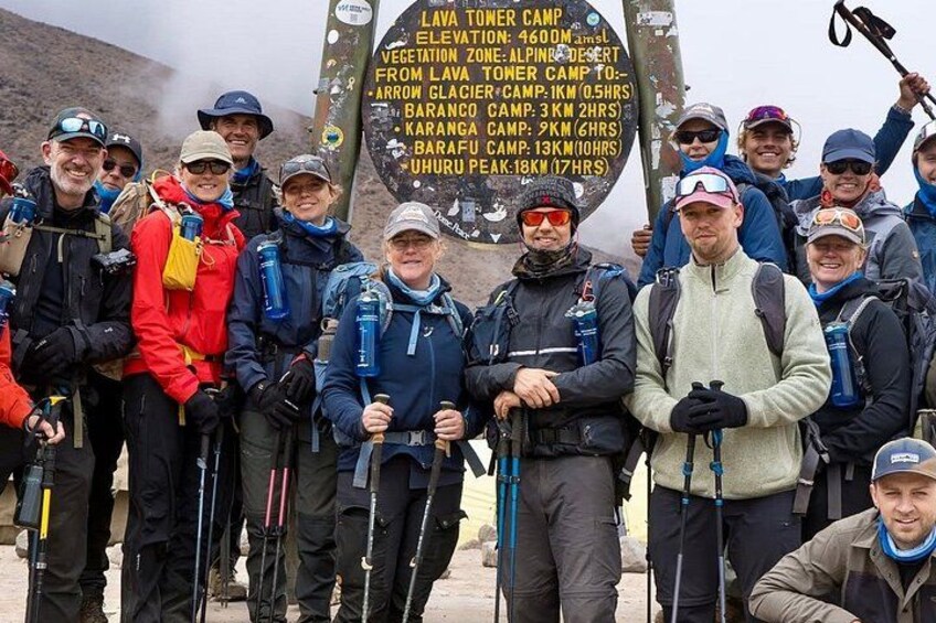 A group of hikers with a sign listing various camps and their elevations. 1