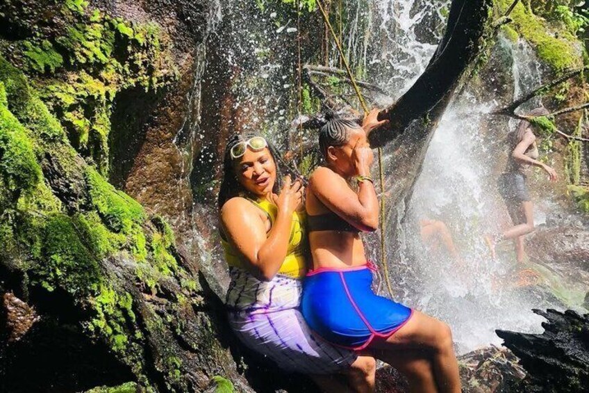 Two people sitting by a waterfall in a forested area. 3