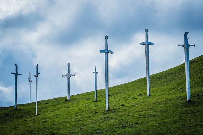 A grassy hill with several swords standing upright. 1