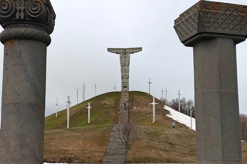 A hill with a cross at the top, surrounded by columns, and a pathway leading up. 3