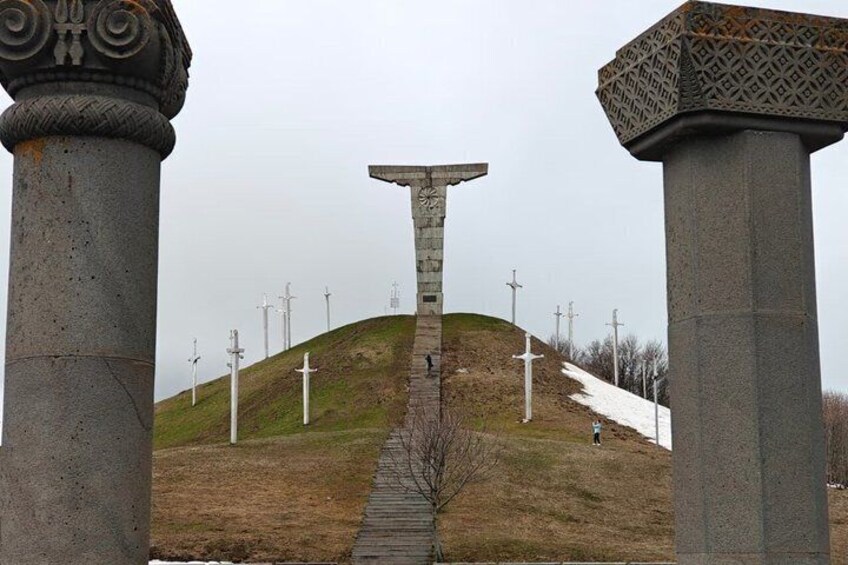 A monument with a cross at the top, flanked by two large columns, with a pathway leading up to it. 3