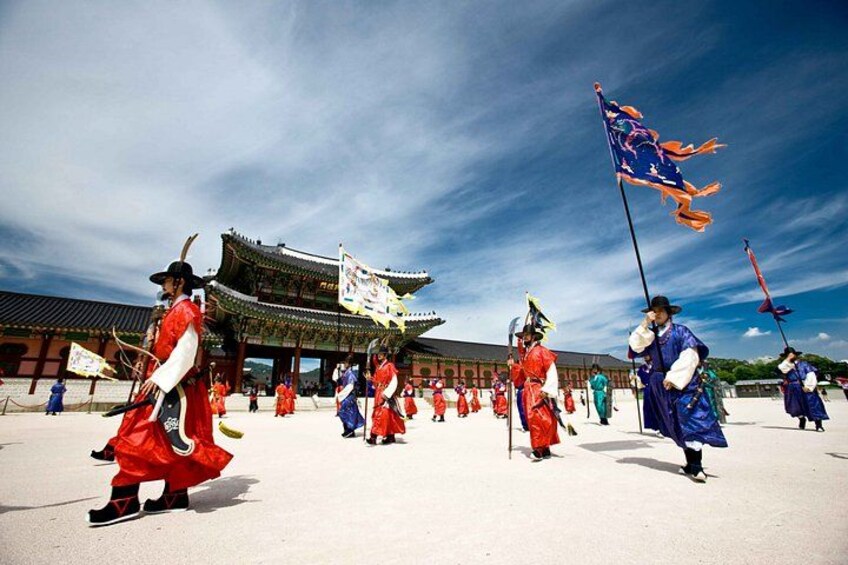People in traditional attire performing a cultural dance in front of a historic building. 3