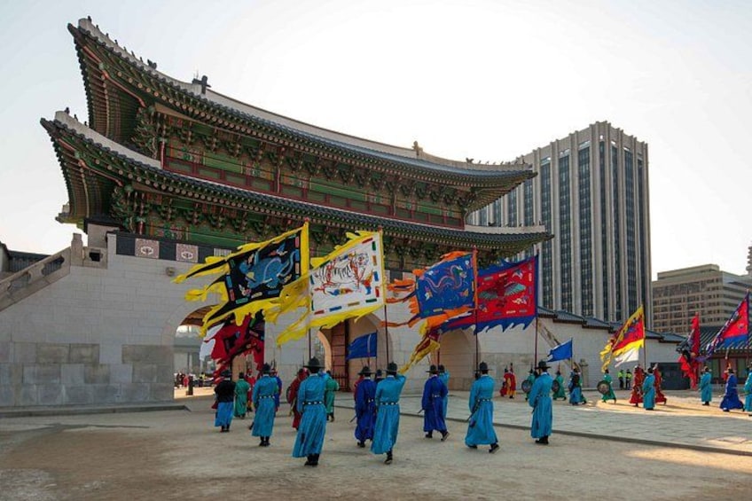 A traditional building with a curved roof, flags, and people in blue attire. 2