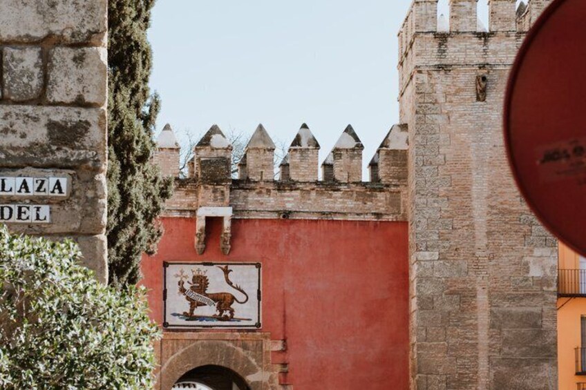 A historic building with a lion emblem, a red wall, and a sign reading 'LAZA DEL.' 5