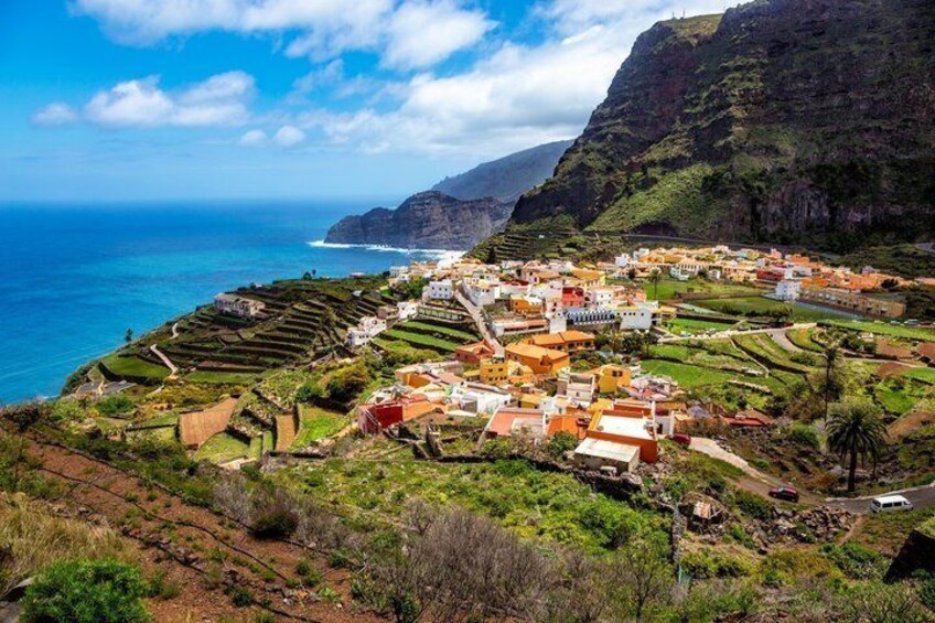 A coastal village with terraced fields, a mountain backdrop, and a clear blue sea. 5