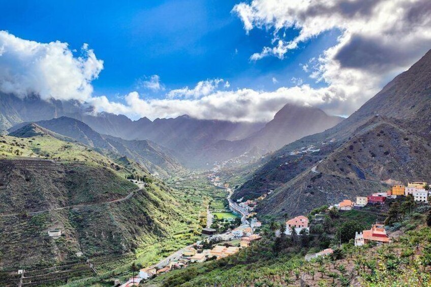 A mountainous landscape with a river, terraced fields, and scattered buildings. 1