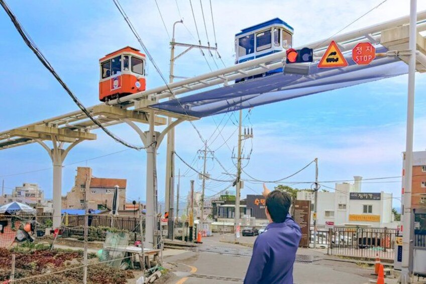 A cable car system with two cars, a pedestrian crossing, and a stop sign. 2