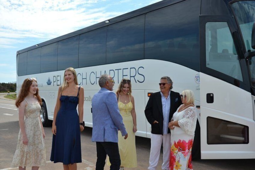 A group of people standing in front of a bus with 'PEI CHARTERS' written on it. 5