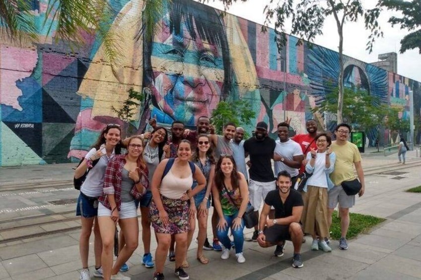 A group of people posing in front of a colorful mural. 1