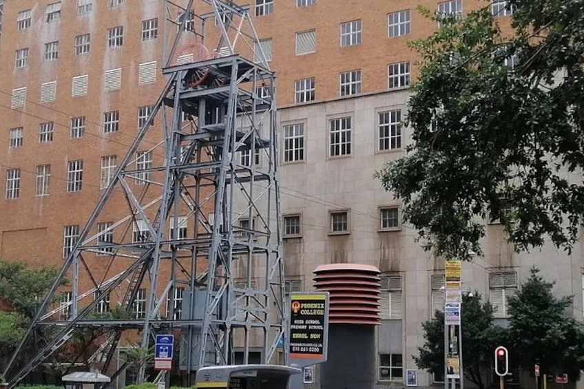A tall metal structure, possibly a crane, in front of a brick building with multiple windows. 2
