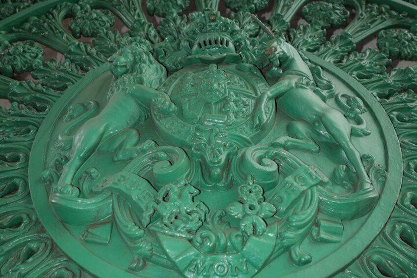 A detailed green metal sculpture with intricate designs and figures. 2