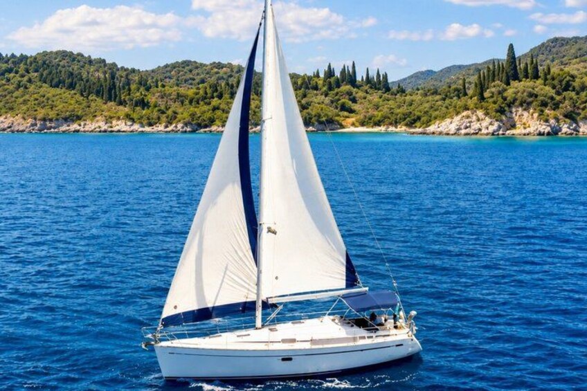 Un velero en un mar tranquilo con una costa montañosa al fondo. 1