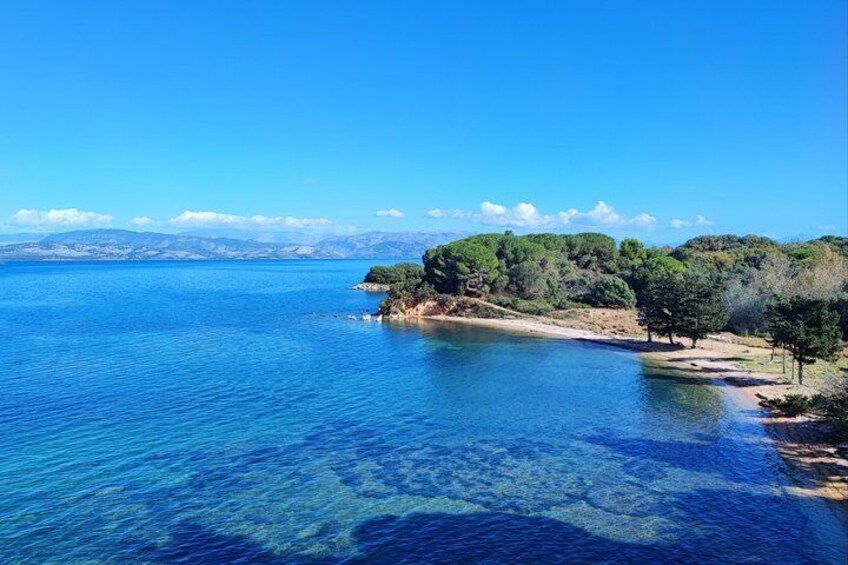 A clear blue sea, a sandy beach, and a forested hill. 4