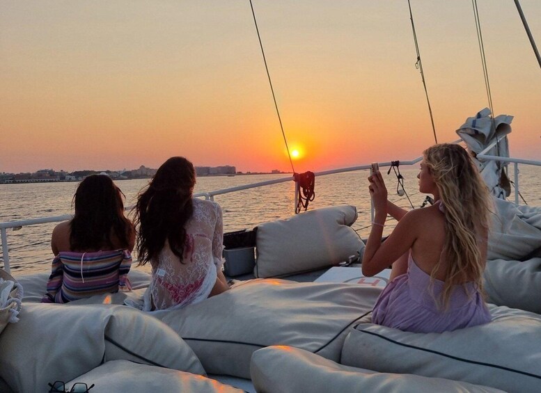 Three individuals on a boat during sunset, with the sun visible in the background. 1