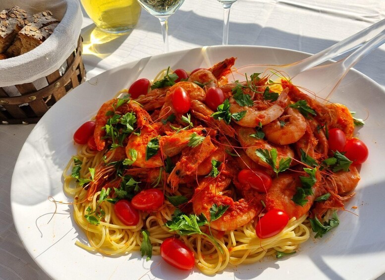 A plate of spaghetti with shrimp and cherry tomatoes garnished with parsley. 4