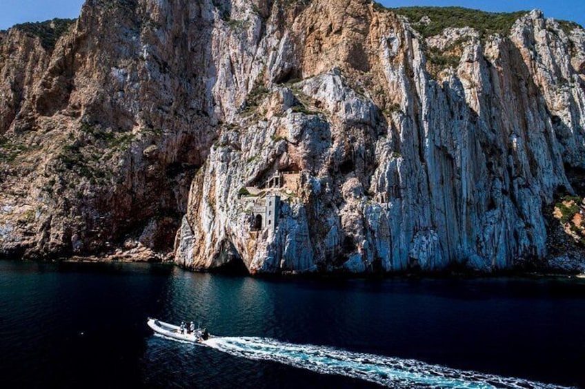 A boat on a calm sea, a rocky cliff, and a clear sky. 5