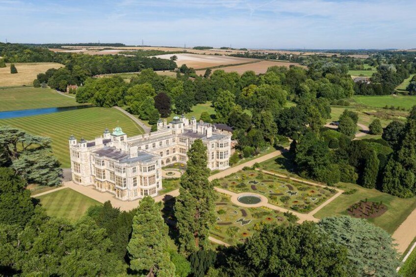 A large, historic mansion surrounded by lush greenery and a well-maintained garden. 1