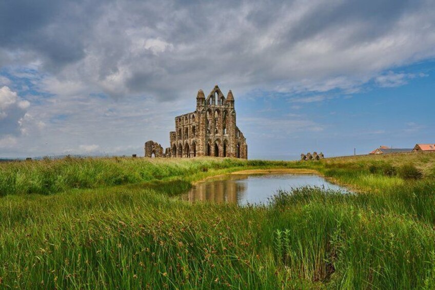 A historic stone building with a pond in the foreground. 1