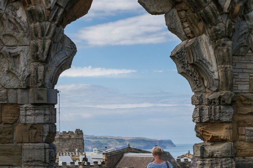 A stone archway with a view of a coastal landscape. 3