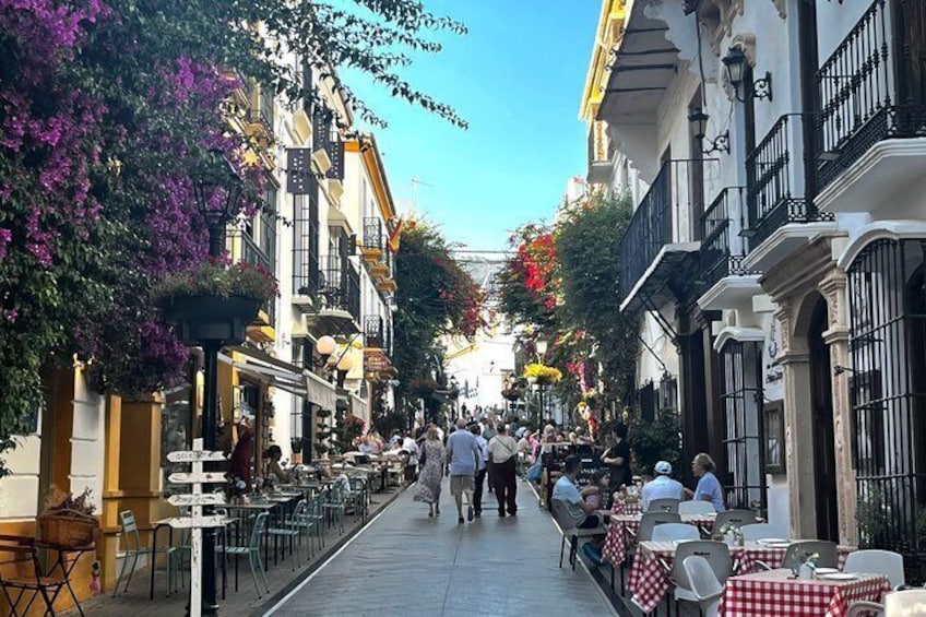 A bustling street lined with cafes, tables, and chairs, with pedestrians walking along. 5