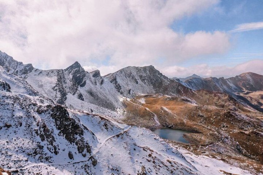 A snow-covered mountain range with a visible lake and rocky terrain. 5