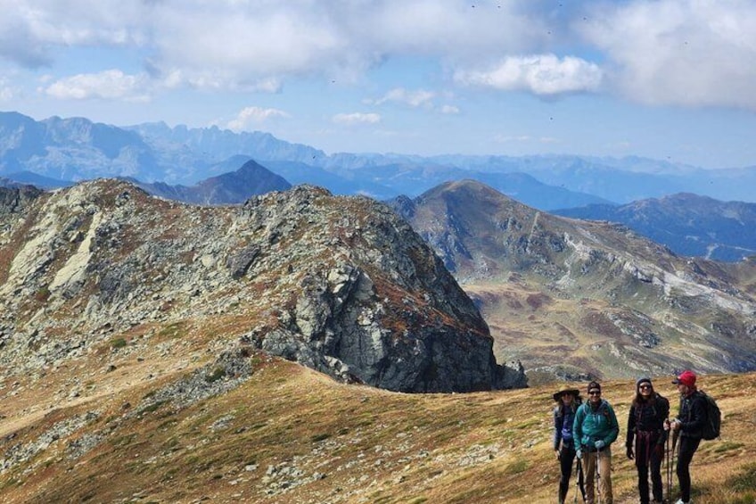 A group of hikers on a mountain trail with rocky terrain and distant mountain ranges. 4