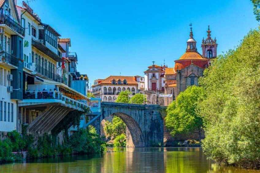 A stone bridge over a river, buildings with red roofs, and a church with a bell tower. 5