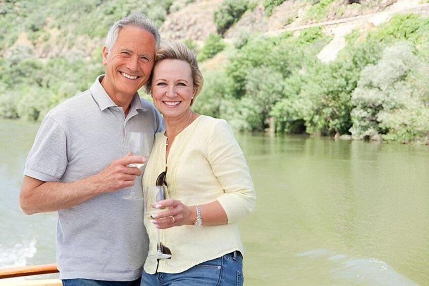 A couple standing by a river with greenery in the background. 1