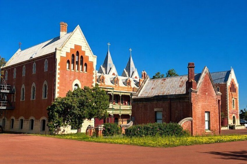 A historic building with a red brick facade, pointed towers, and a large arched entrance. 2