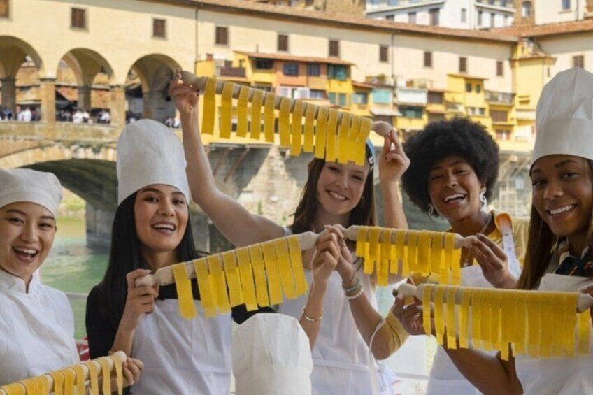 A group of people in white chef hats holding yellow pasta strips. 1