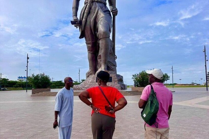 A statue in a public square with three people observing it. 4