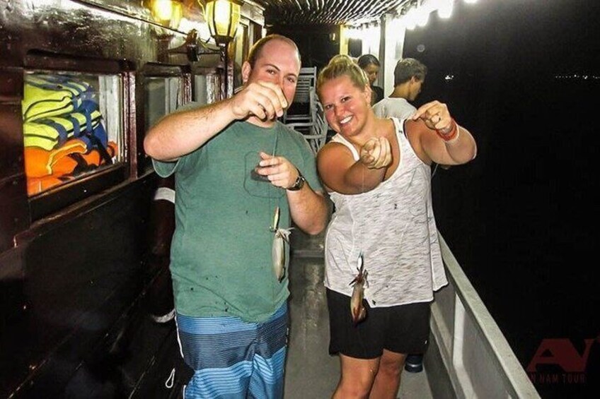 Two people on a boat holding fish. 1