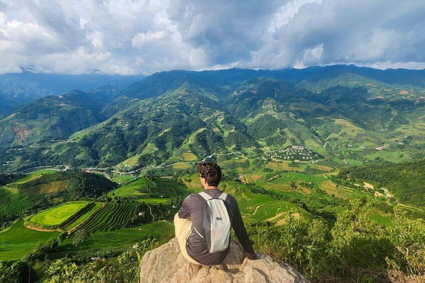 A person sitting on a rock overlooking a mountainous landscape with terraced fields. 5