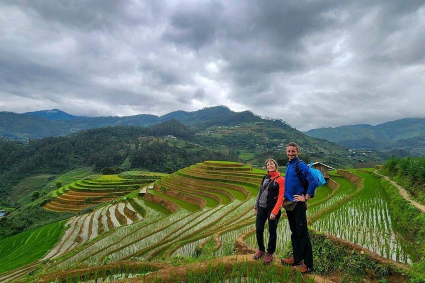 Terraced rice fields, a person in a blue jacket, and a person in a red jacket. 1