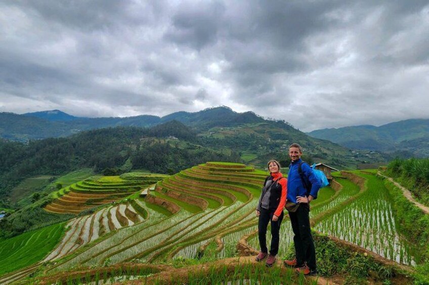 Terraced rice fields, a person with a backpack, and a cloudy sky. 1