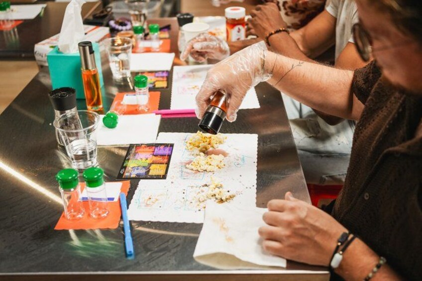 A person pouring a liquid from a bottle onto a paper on a table. 5