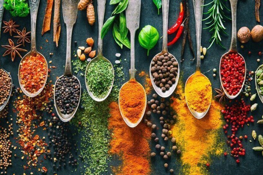 Various spices and herbs in spoons on a dark surface. 4