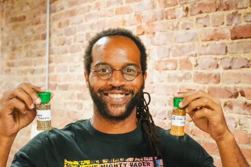 A person holding two spice jars against a brick wall background. 4