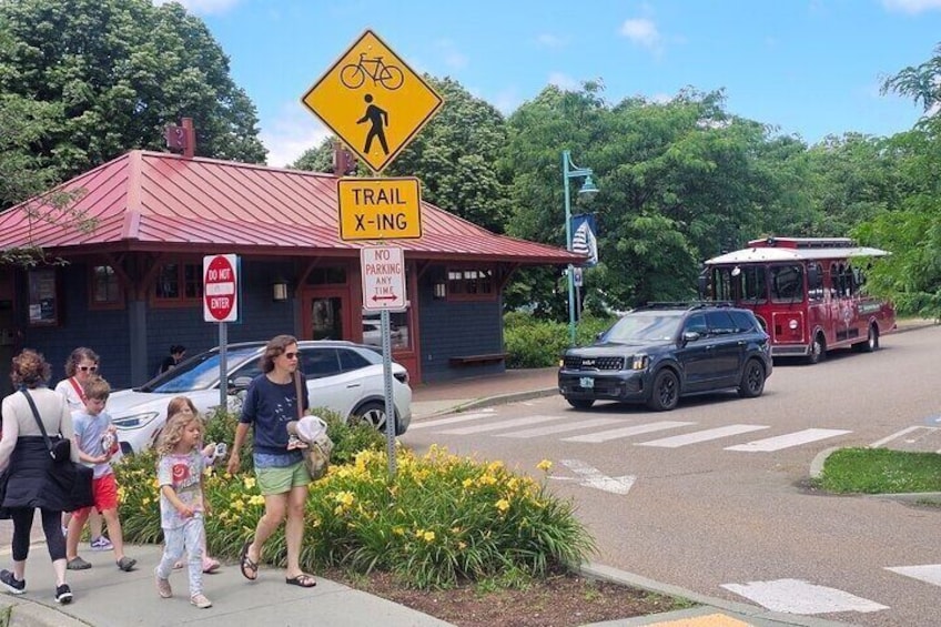A trail crossing sign, a no parking sign, a red building, and a vehicle on the road. 4