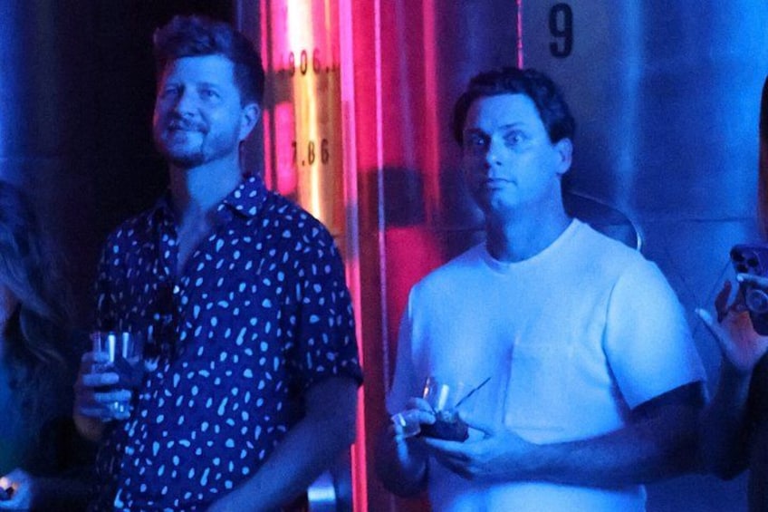 Two people standing in a dimly lit room with a red and blue light. 2