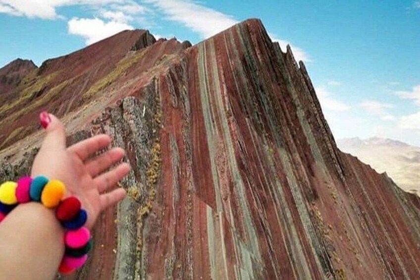 A hand reaching out to touch a striped rock formation. 3