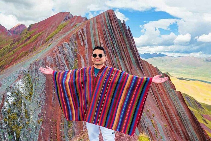 Una persona de pie con los brazos extendidos frente a una cadena montañosa. 5
