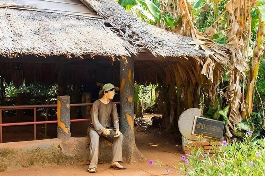 A person sitting on a bench under a thatched structure surrounded by tropical vegetation. 4