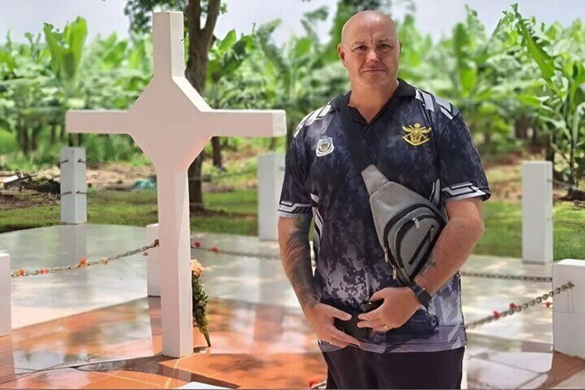 A person standing in a cemetery with a white cross monument. 5