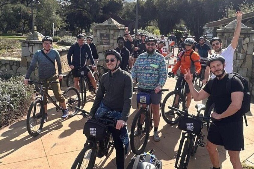 A group of people on bicycles in a park with stone structures and greenery. 4