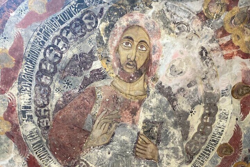A mosaic with a central figure holding a book, surrounded by intricate patterns and inscriptions. 4